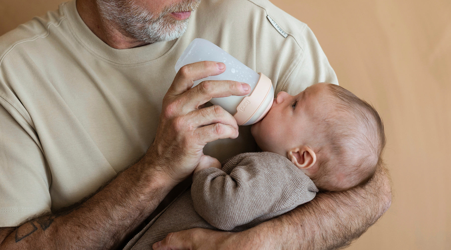Vader geeft zijn baby de Mammafeel fles, een borstvoedingsvriendelijke siliconen fles voor comfortabel drinken