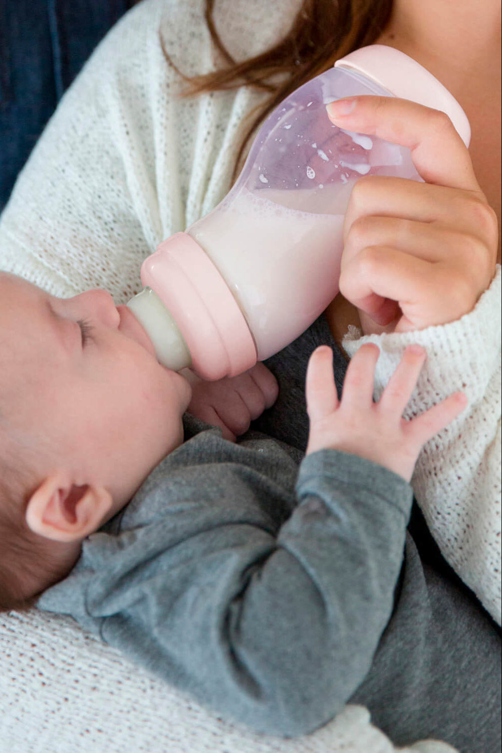 Baby wordt gevoed met roze Difrax S-fles 310ml, rustgevend voedingsmoment met moeder in comfortabele houding