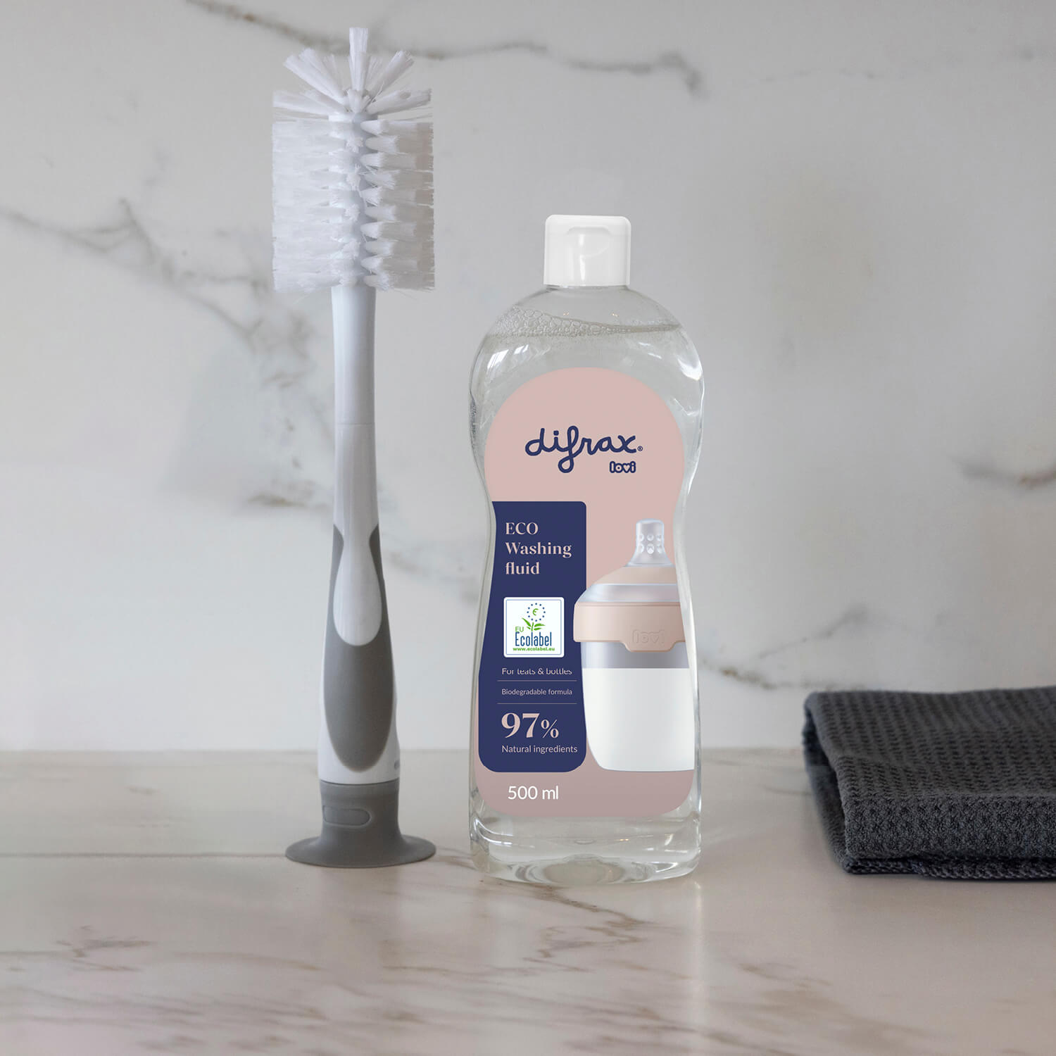 Fles ECO afwasmiddel voor babyproducten met afwasborstel en handdoek.