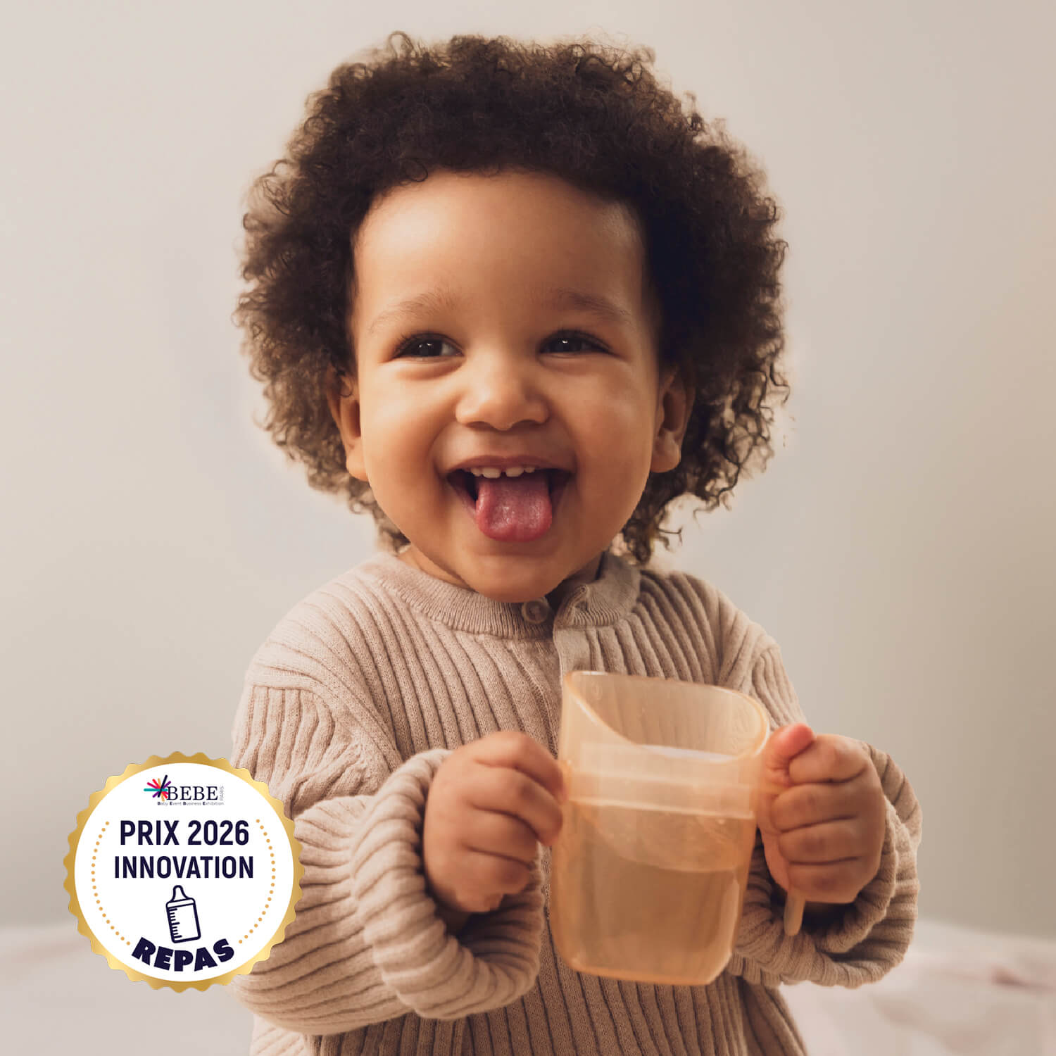 Jong meisje houdt de Difrax LOVI Genius Cup vast in de kleur Nude, winnaar van de Prix 2026 Innovation Award, ontworpen voor kinderen vanaf 6 maanden om zelfstandig te leren drinken met een natuurlijke, veilige drinkhouding.