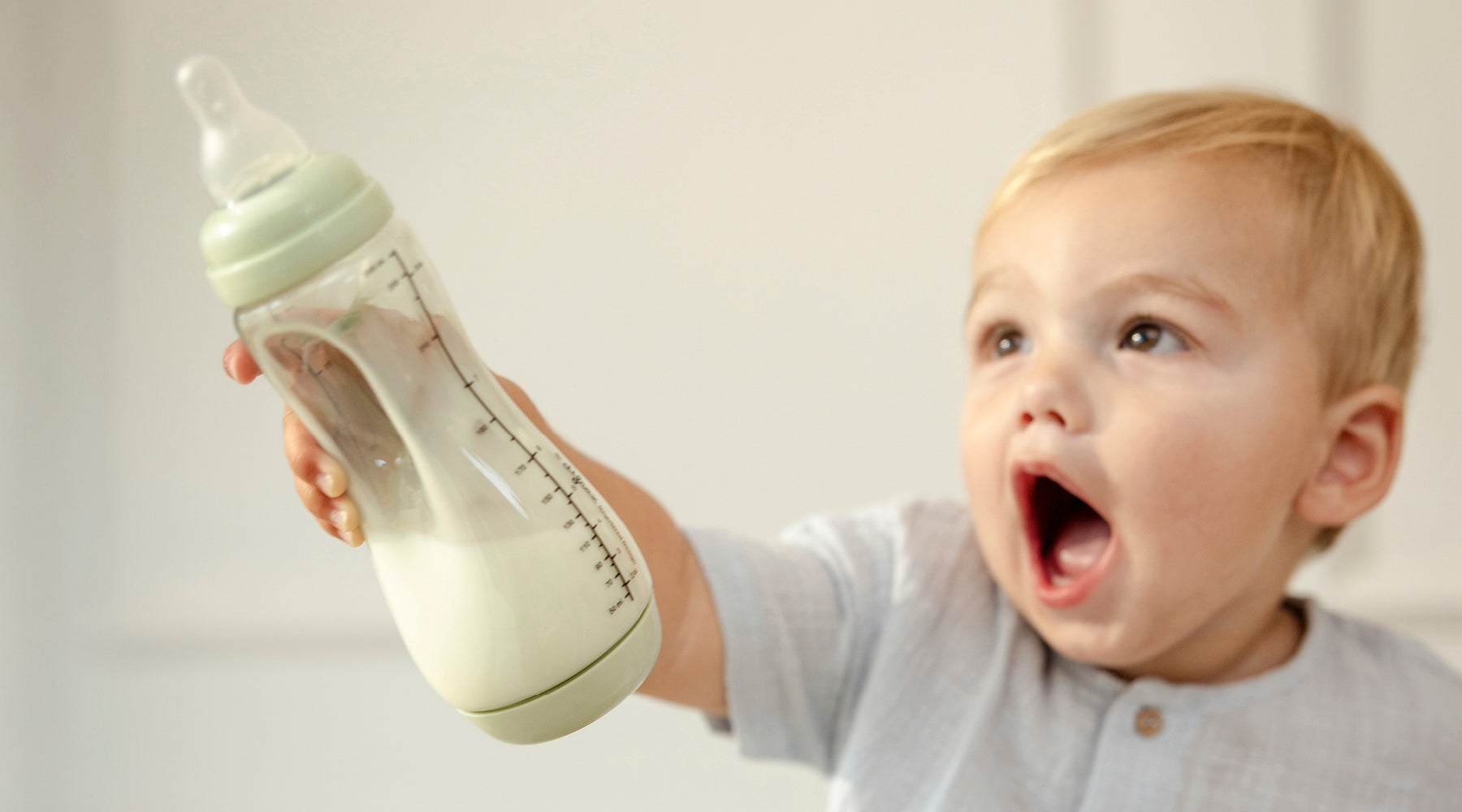 Baby houdt een Difrax Handgreep babyfles vast, ideaal voor kleine handjes en het leren zelfstandig drinken.