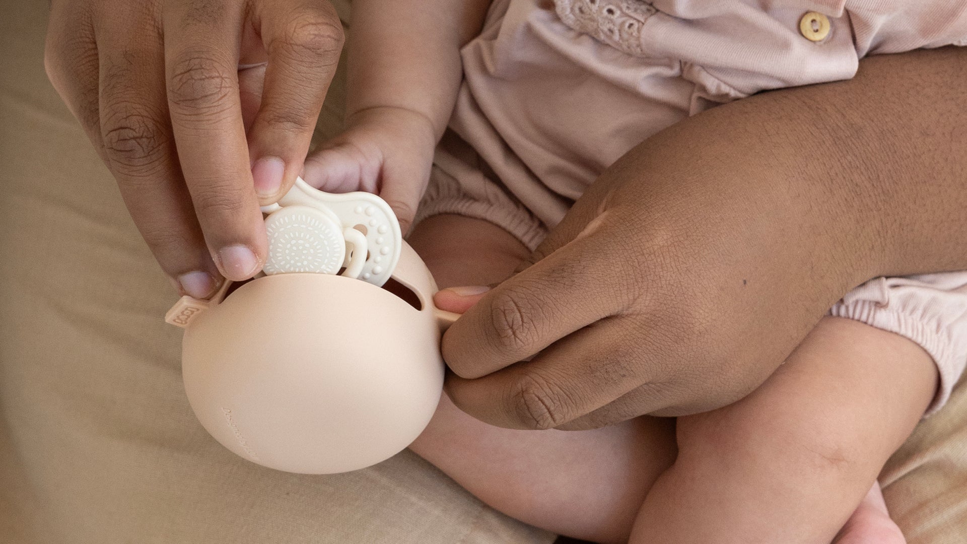 Une jeune fille est assise à une table de déjeuner. Elle porte leBoite à sucette en silicone Difrax LOVI nu
