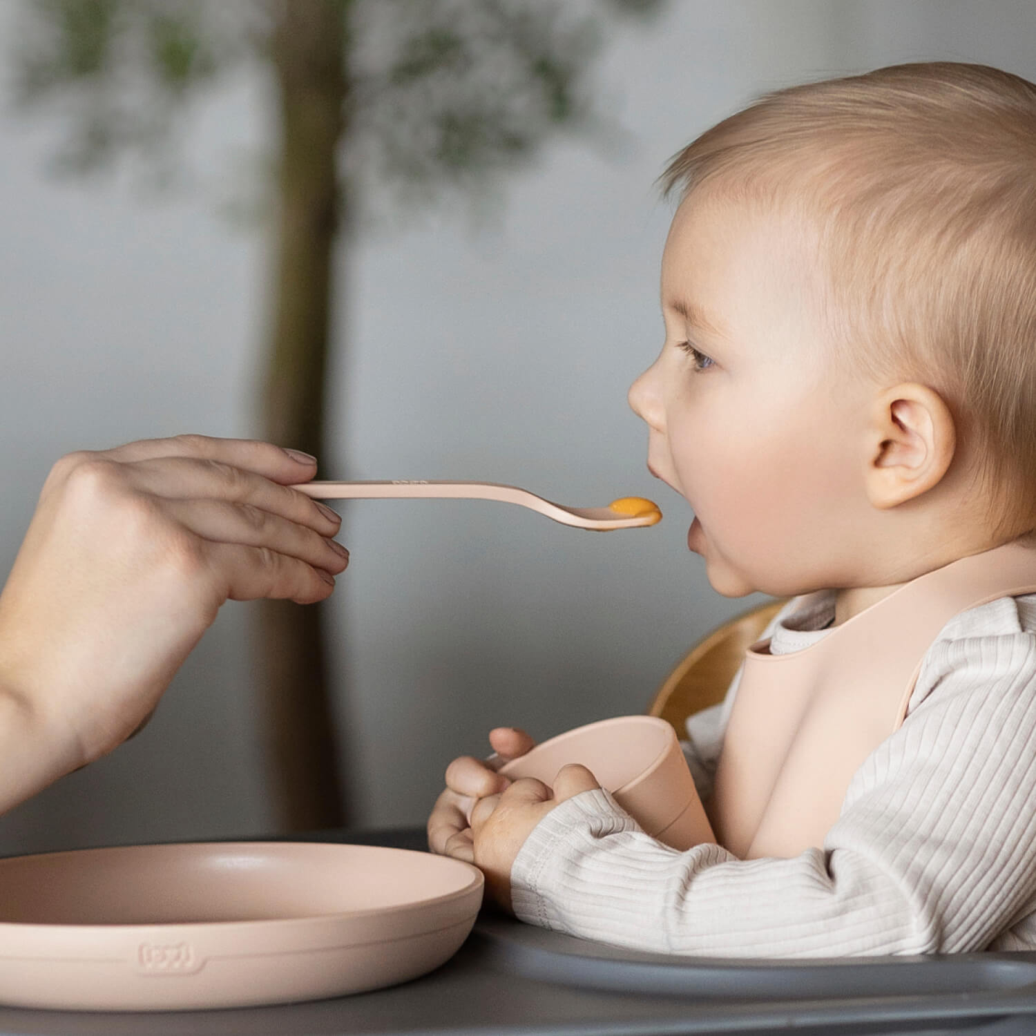 Kind met de Difrax LOVI Baby Eet- & Drinkset Nude – bord, kom, open beker, lepels en siliconen slab zichtbaar tijdens het eetmoment.